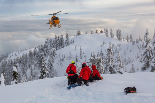 North Shore Search and Rescue helicopter flying in to a group of SAR members on a ski hill