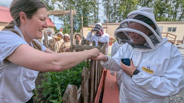 A guide educating a person wearing beekeeping suite at the Honeybee Centre, Outdoor Experience.